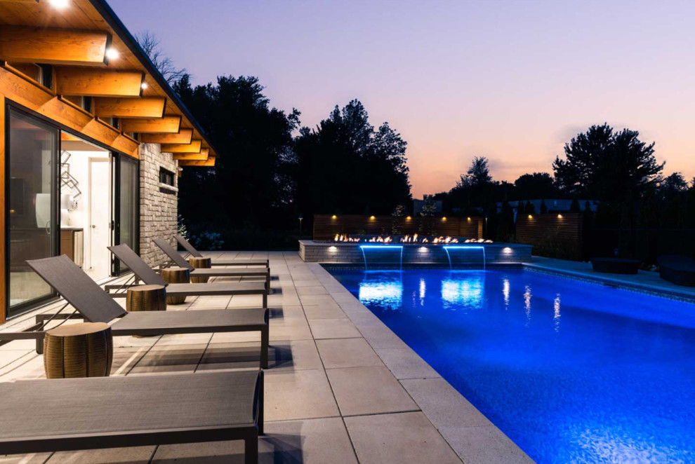 Esempio di una grande piscina monocorsia design rettangolare dietro casa con fontane e pavimentazioni in cemento