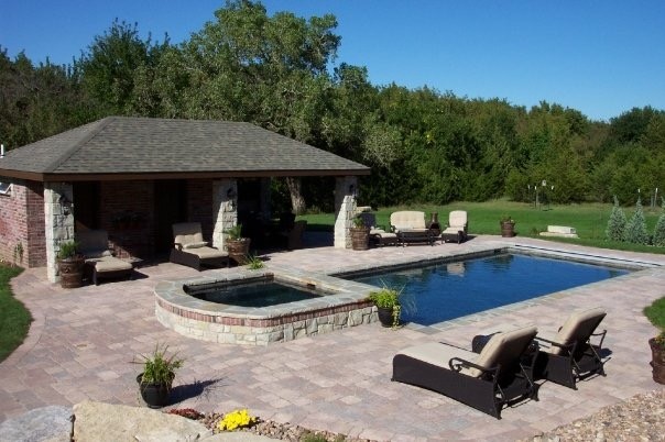 Idée de décoration pour une grande piscine naturelle et arrière chalet sur mesure avec un bain bouillonnant et des pavés en pierre naturelle.