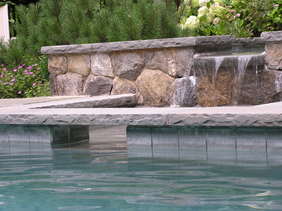 This is an example of a large back custom shaped natural hot tub in New York with natural stone paving.