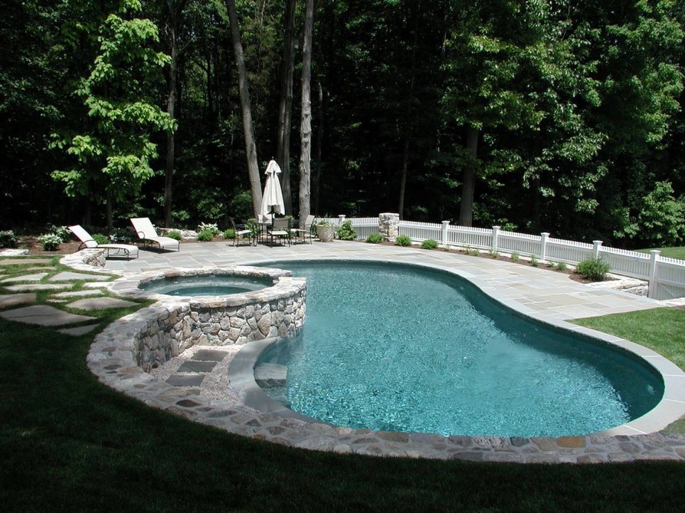 Diseño de piscinas y jacuzzis naturales grandes tipo riñón en patio trasero con adoquines de piedra natural
