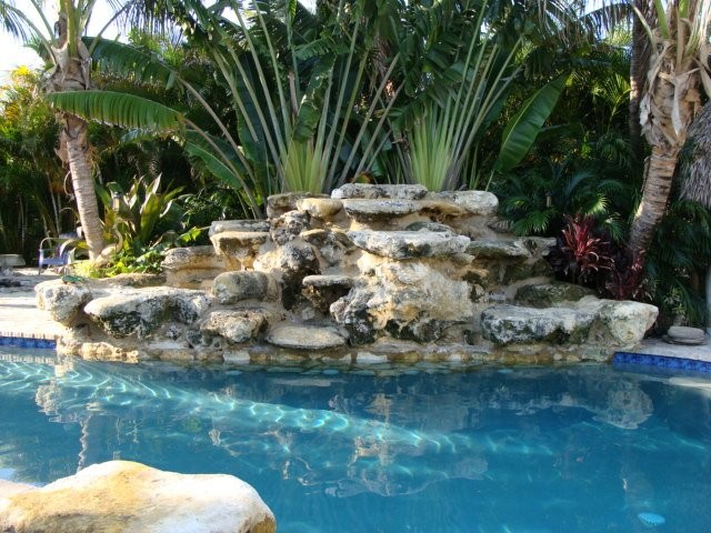 Idee per una piscina tropicale personalizzata di medie dimensioni e dietro casa con fontane e pavimentazioni in pietra naturale