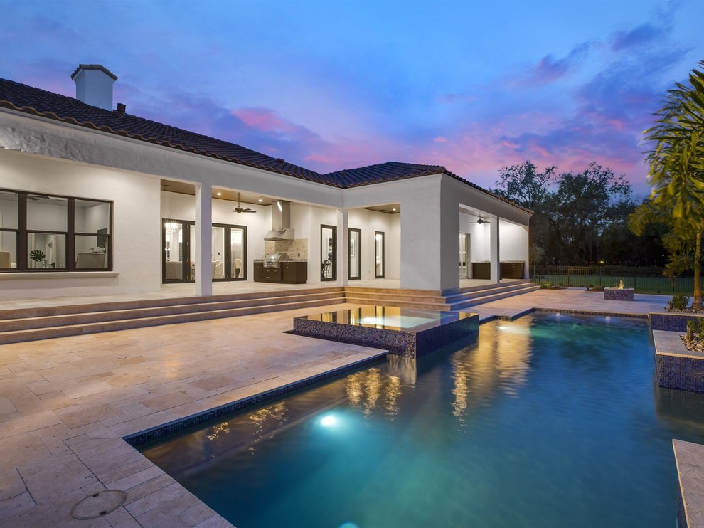 Großer Mediterraner Pool hinter dem Haus in rechteckiger Form mit Natursteinplatten in Orlando