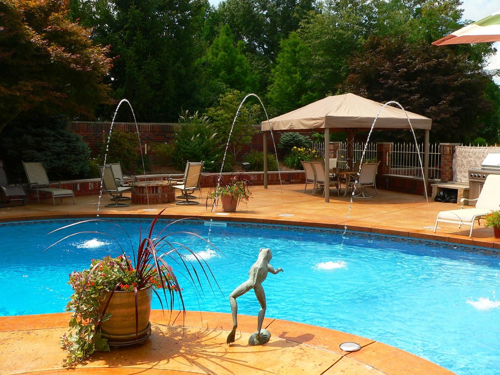 Imagen de casa de la piscina y piscina tradicional grande tipo riñón en patio trasero con adoquines de piedra natural