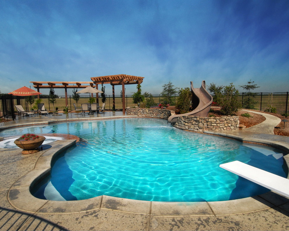 Esempio di una grande piscina tradizionale personalizzata dietro casa con un acquascivolo e lastre di cemento