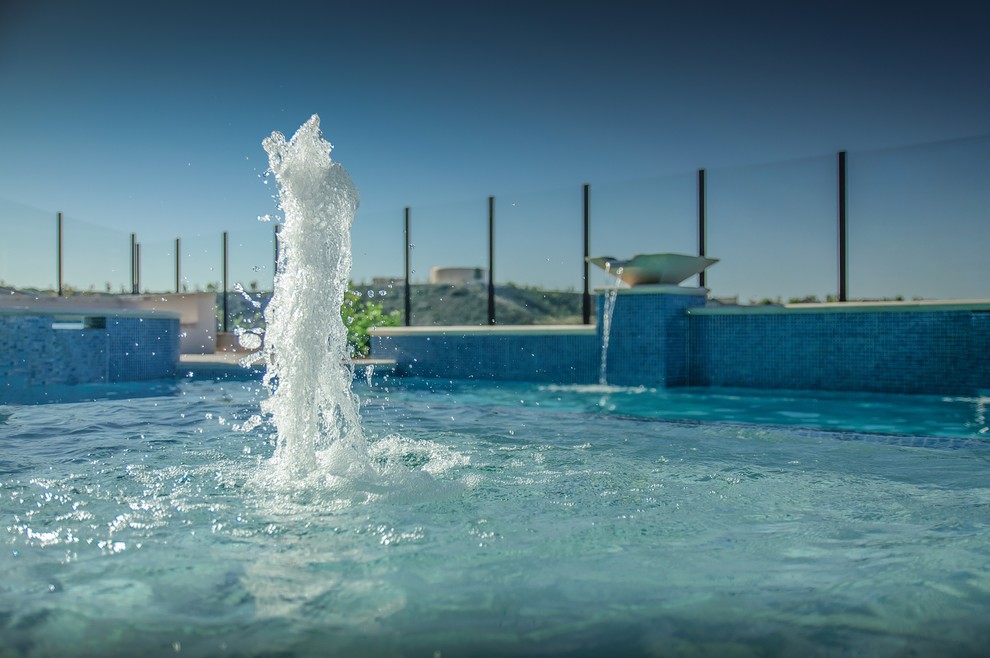 Пример оригинального дизайна: большой спортивный, прямоугольный бассейн на заднем дворе в современном стиле с фонтаном и покрытием из бетонных плит