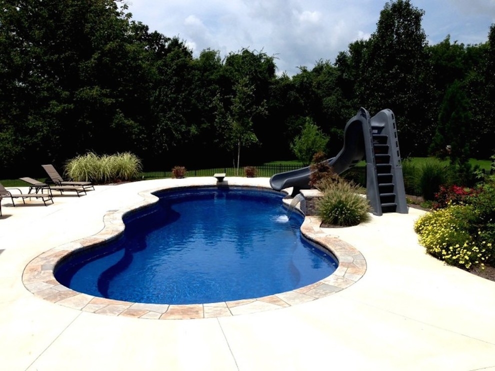 Foto di una piscina chic personalizzata di medie dimensioni e dietro casa con un acquascivolo e lastre di cemento