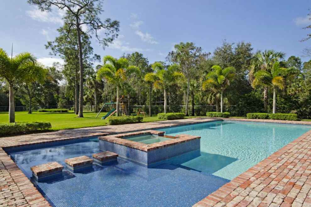 Inspiration for a large classic back rectangular lengths hot tub in Miami with brick paving.