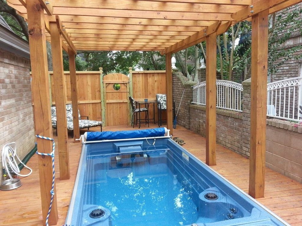 Réalisation d'une grande piscine tradition rectangle avec un bain bouillonnant et une terrasse en bois.