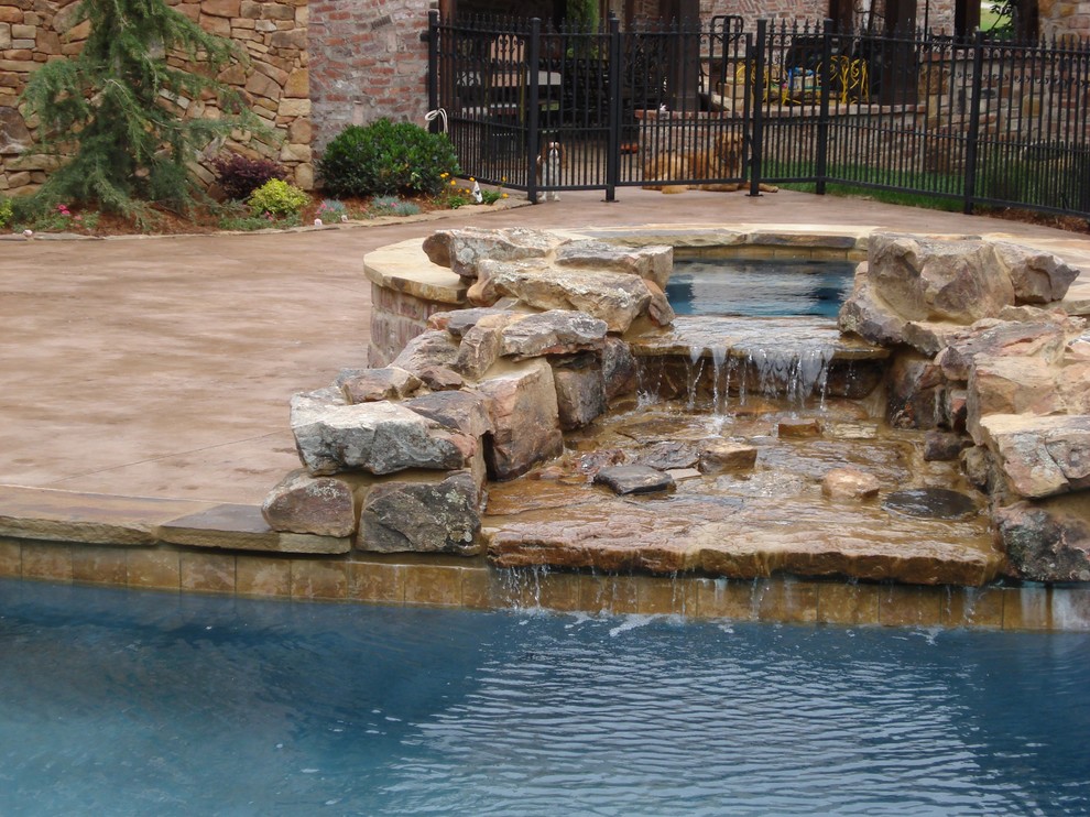 На фото: большой бассейн произвольной формы на заднем дворе в классическом стиле с покрытием из бетонных плит