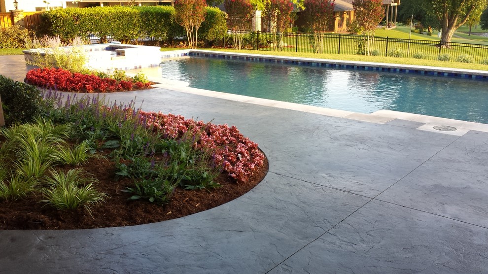 Imagen de piscina clásica extra grande rectangular en patio trasero con losas de hormigón