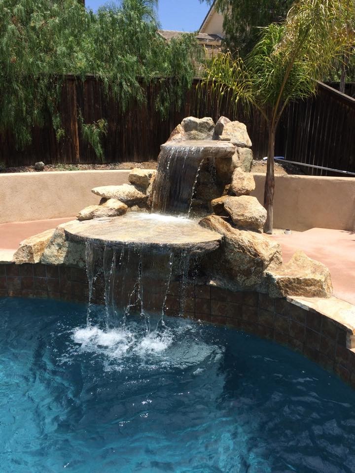 This is an example of a medium sized contemporary back custom shaped lengths swimming pool in Los Angeles with a water feature and concrete slabs.