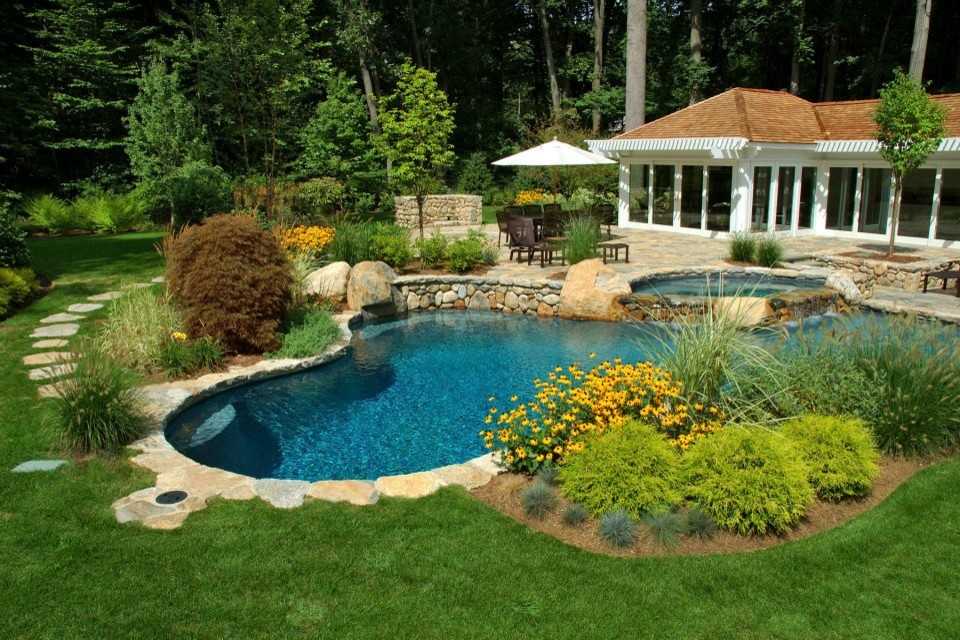 Exemple d'une piscine arrière chic en forme de haricot de taille moyenne avec un bain bouillonnant et des pavés en pierre naturelle.