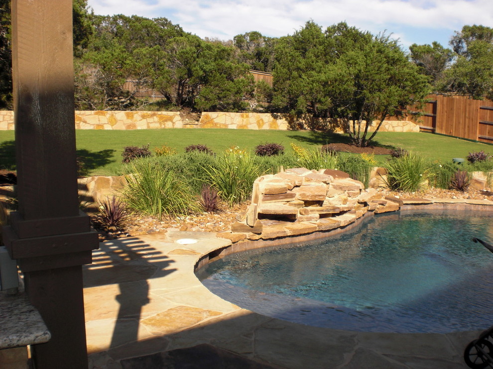 Imagen de piscina con fuente tradicional de tamaño medio a medida en patio trasero con adoquines de piedra natural