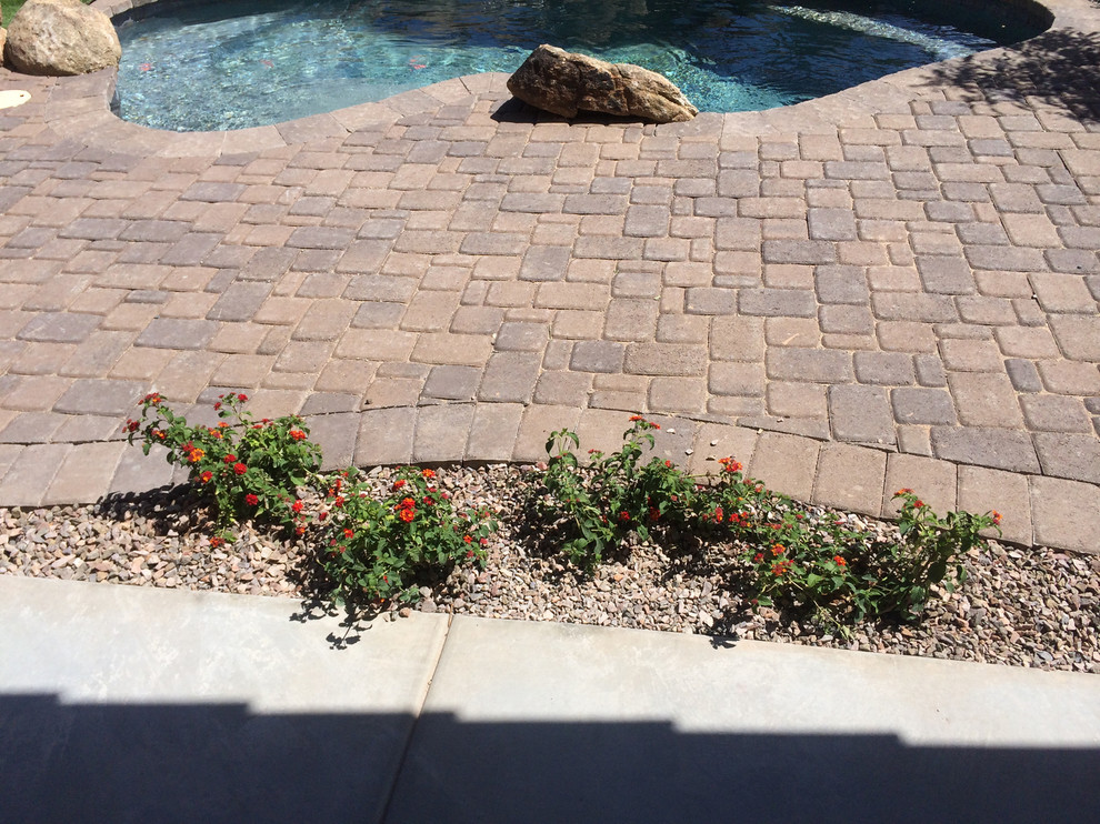 Diseño de piscinas y jacuzzis de estilo americano grandes en forma de L en patio trasero con adoquines de piedra natural