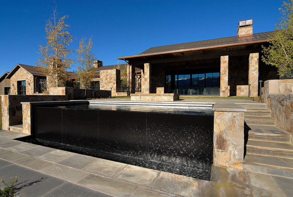 Ejemplo de piscinas y jacuzzis infinitos rurales grandes rectangulares en patio trasero con adoquines de piedra natural
