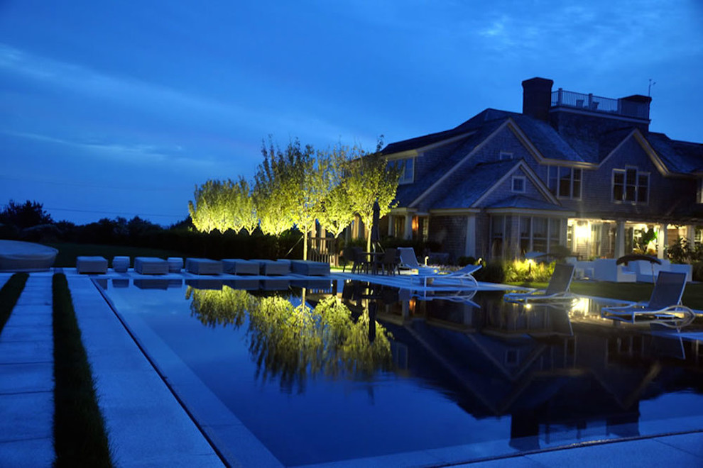 Immagine di un'ampia piscina a sfioro infinito minimal rettangolare dietro casa con lastre di cemento