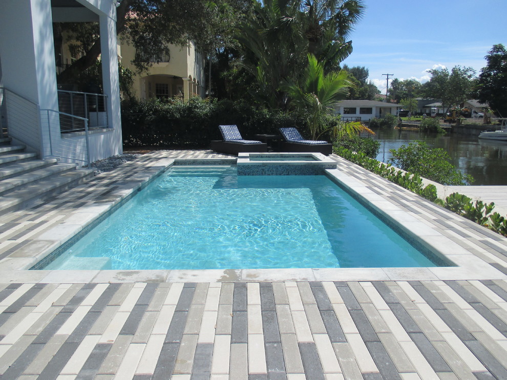 Exemple d'une piscine arrière exotique rectangle et de taille moyenne avec des pavés en béton.