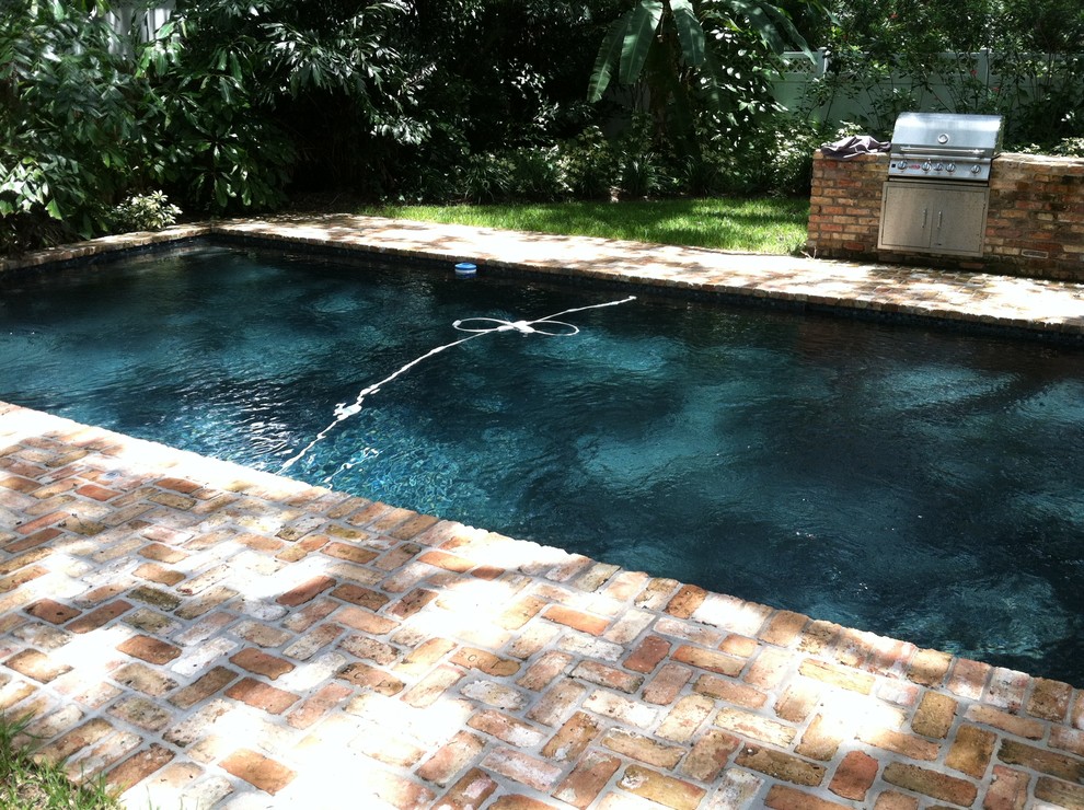 Medium sized world-inspired back custom shaped swimming pool in Tampa with brick paving.