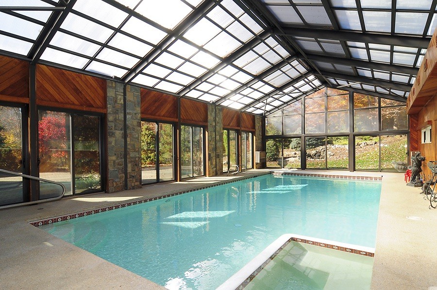 Foto di una grande piscina coperta monocorsia classica rettangolare con una dépendance a bordo piscina e lastre di cemento