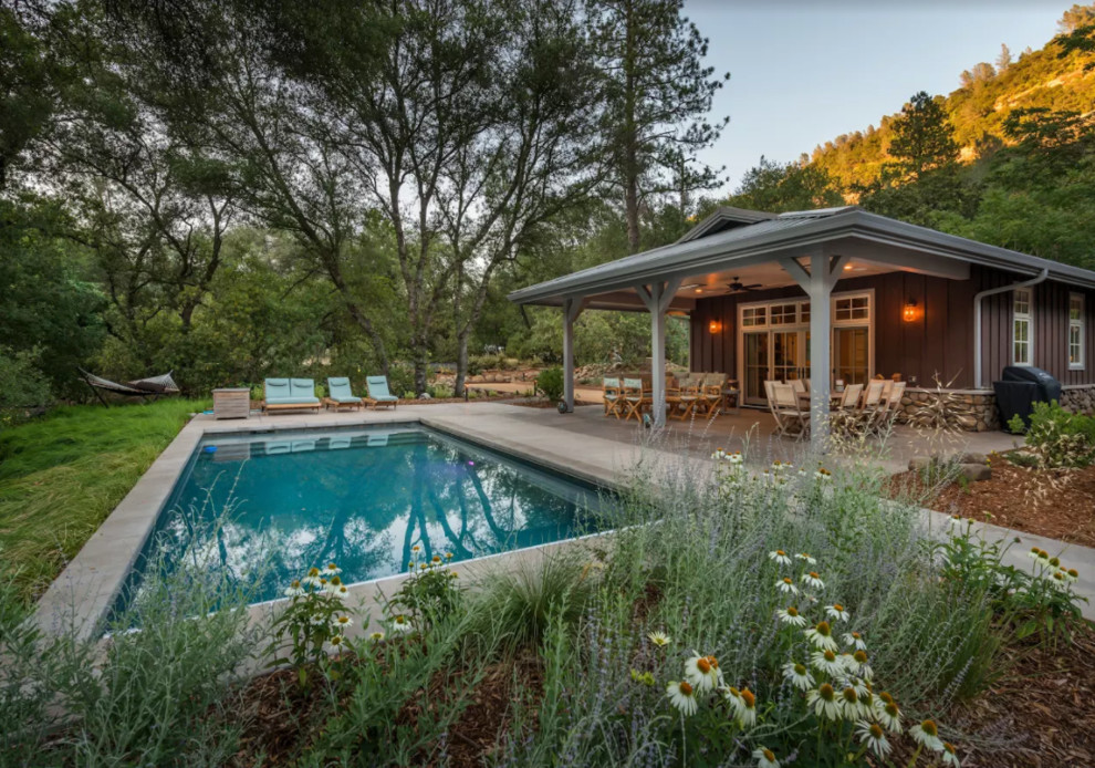 Imagen de piscina alargada campestre de tamaño medio rectangular en patio trasero con losas de hormigón