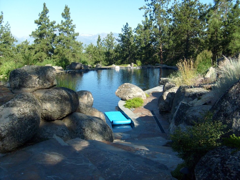 Idées déco pour une grande piscine arrière et naturelle craftsman sur mesure avec des pavés en pierre naturelle.