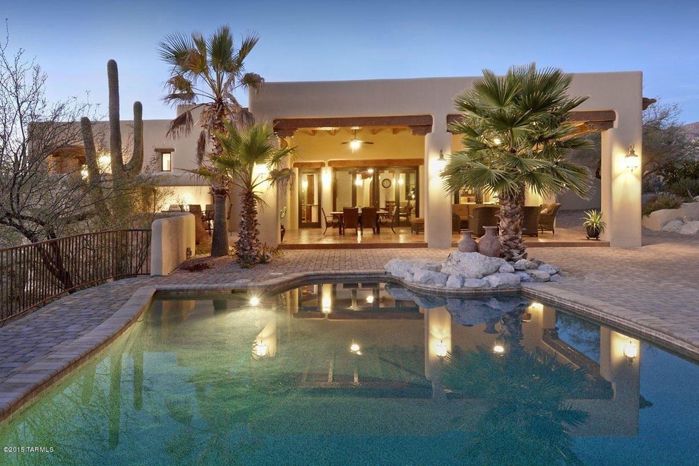 Foto de piscina alargada de estilo americano grande a medida en patio trasero con adoquines de piedra natural