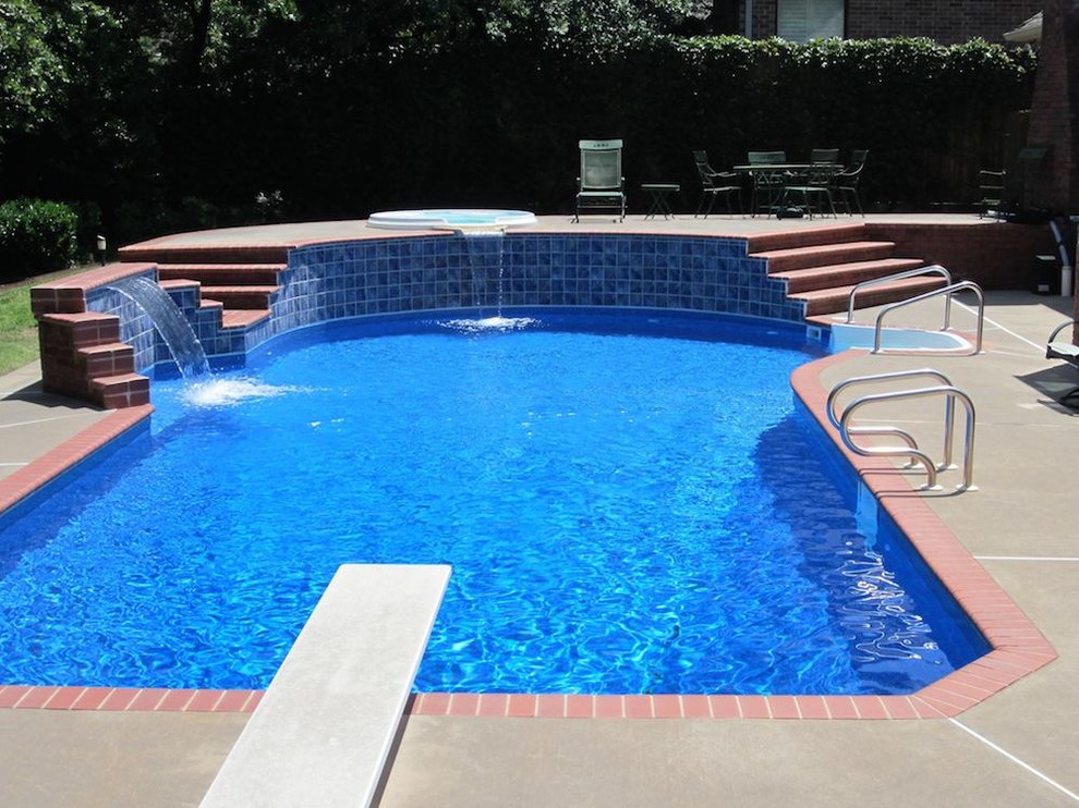 Diseño de piscina con fuente alargada tropical de tamaño medio en patio trasero