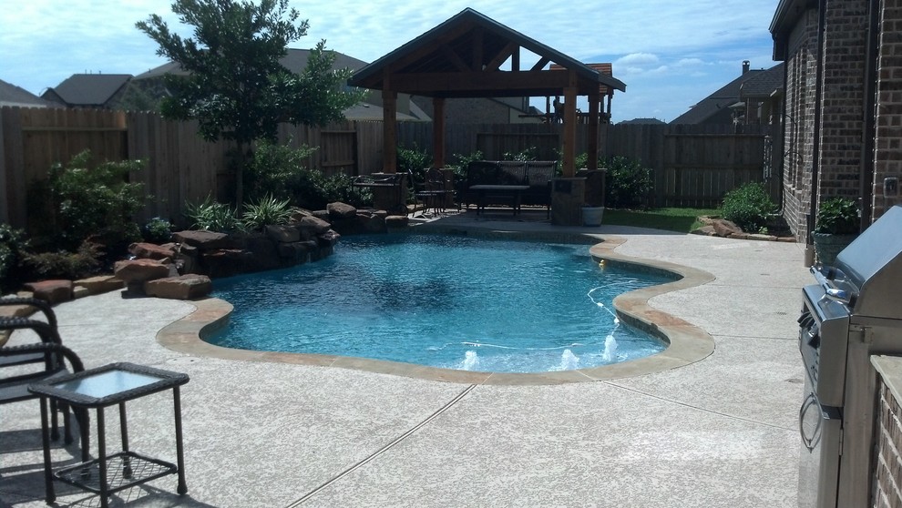 Example of a mid-sized classic backyard concrete and custom-shaped natural hot tub design in Houston