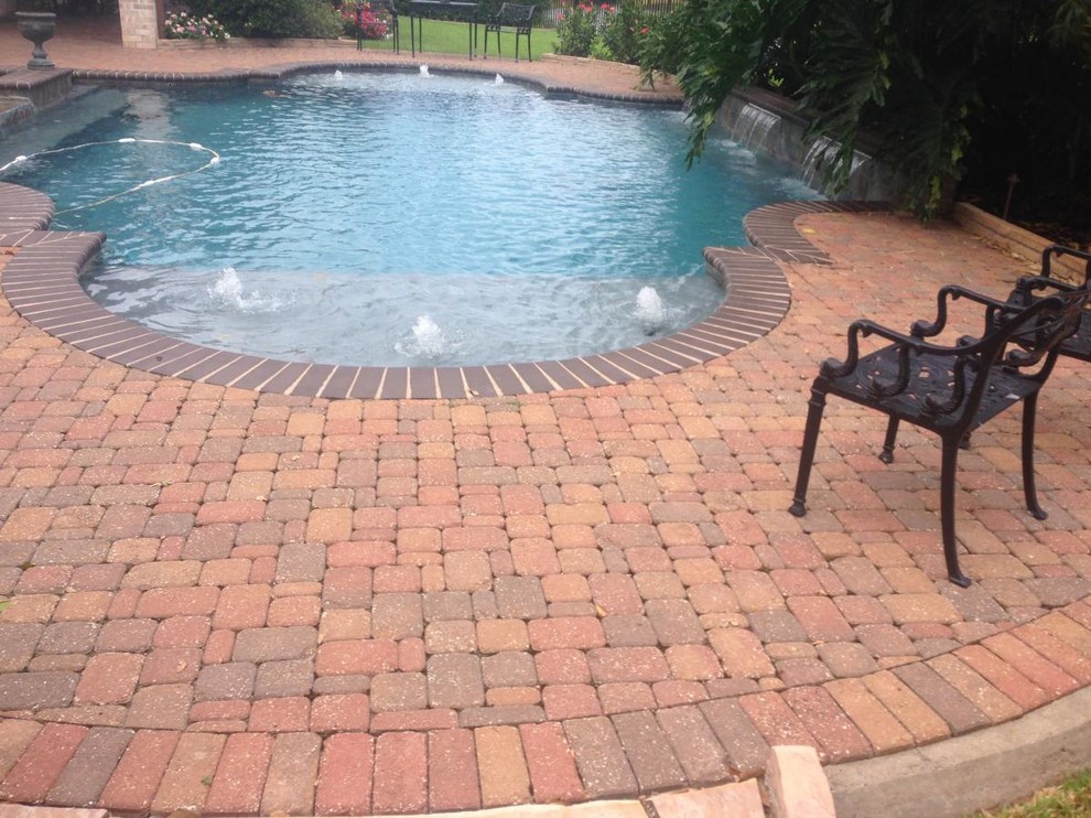 Diseño de piscina con fuente clásica de tamaño medio a medida en patio trasero con adoquines de ladrillo