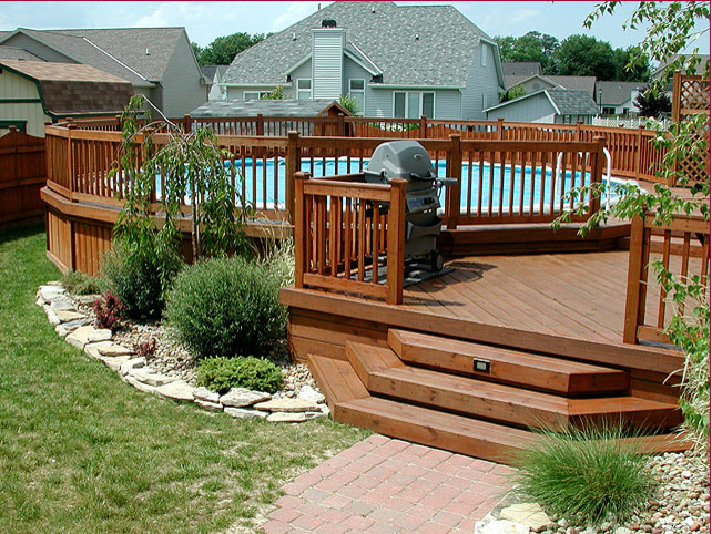 Diseño de piscina elevada de tamaño medio redondeada en patio trasero con entablado