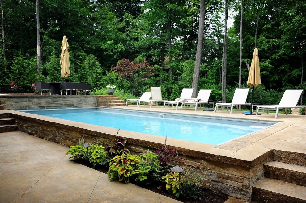 Esempio di una piscina monocorsia design rettangolare di medie dimensioni e dietro casa con una vasca idromassaggio e cemento stampato