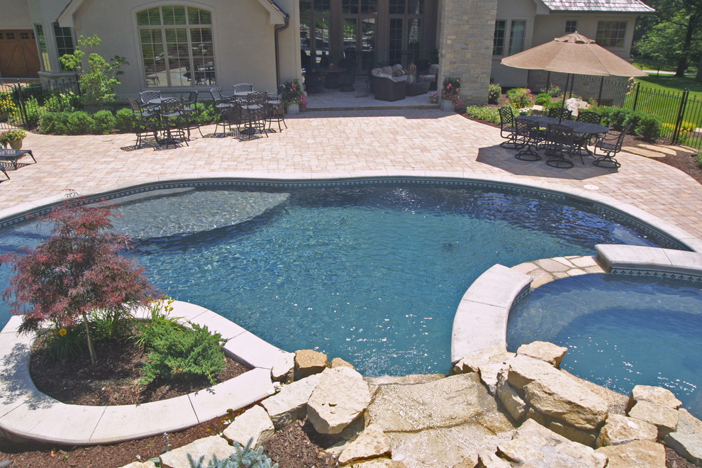 Photo of a medium sized mediterranean back round hot tub in St Louis with concrete paving.
