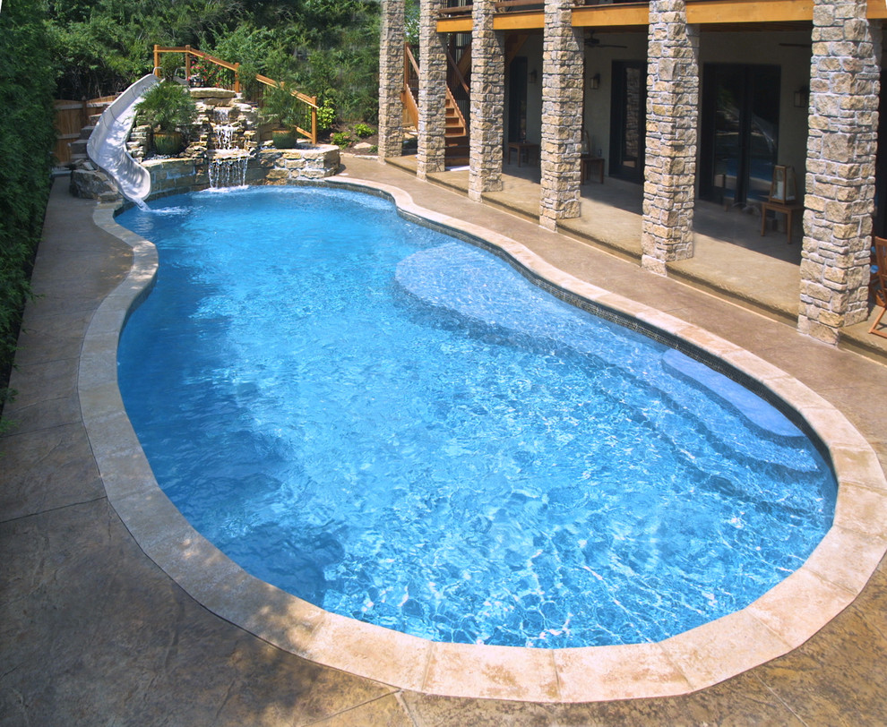 Ejemplo de piscina con tobogán mediterránea de tamaño medio a medida en patio trasero con adoquines de piedra natural