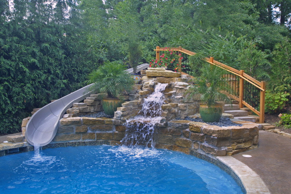 Exempel på en mellanstor modern anpassad pool på baksidan av huset, med vattenrutschkana och naturstensplattor