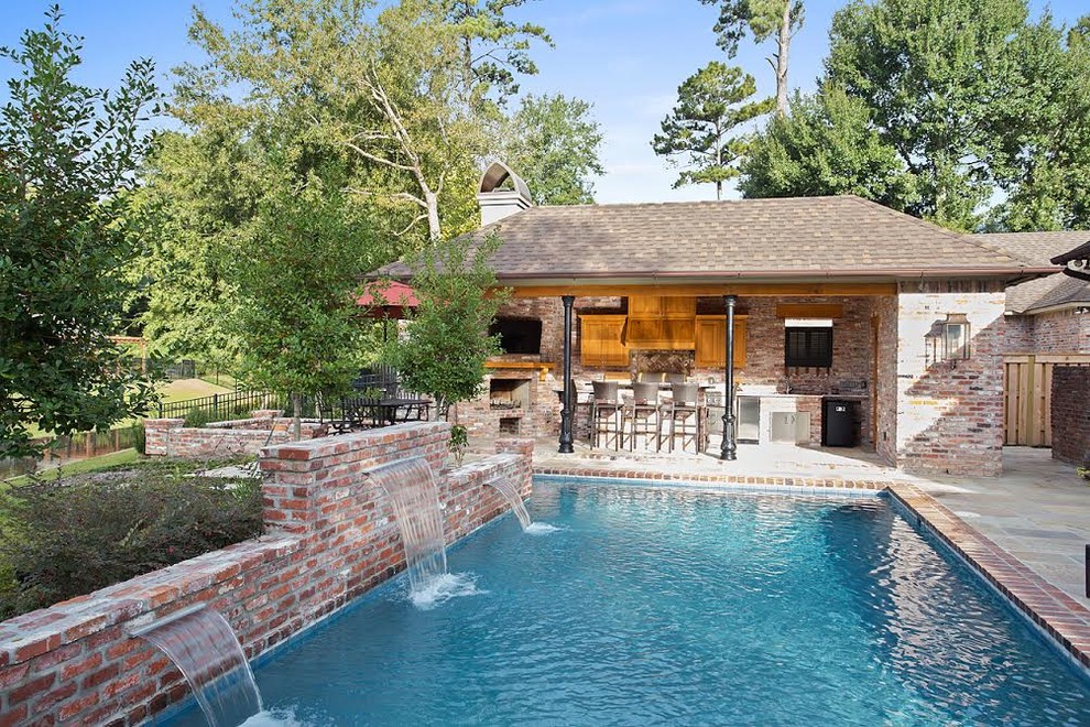 Modelo de piscina con fuente alargada tradicional de tamaño medio rectangular en patio trasero con adoquines de ladrillo