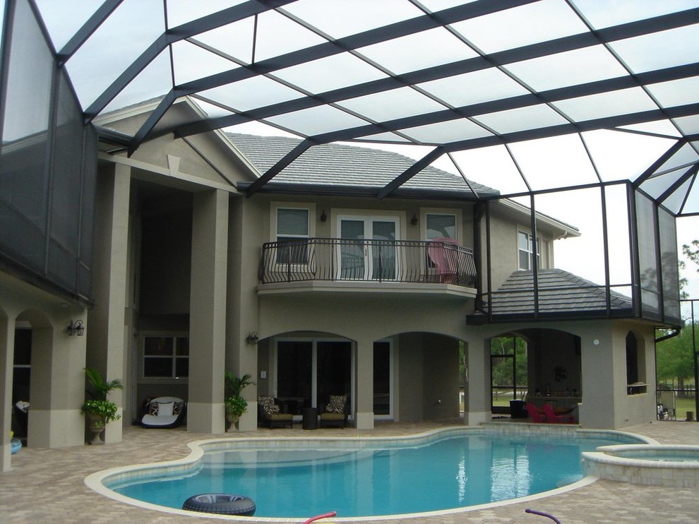 Пример оригинального дизайна: большой бассейн произвольной формы в доме в классическом стиле с джакузи и мощением тротуарной плиткой