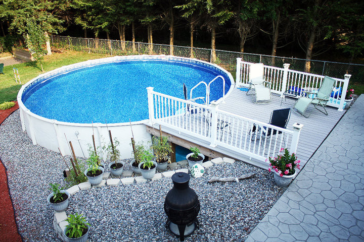 Diseño de piscina elevada de tamaño medio redondeada en patio trasero con entablado