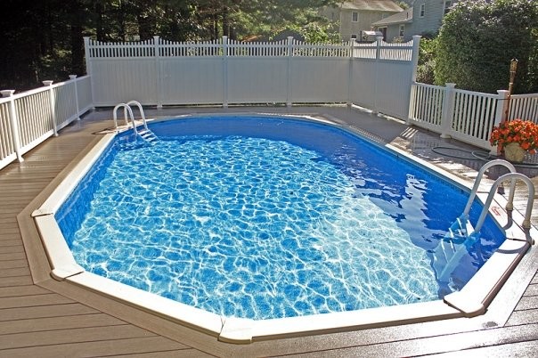Diseño de piscina de tamaño medio redondeada en patio trasero con entablado