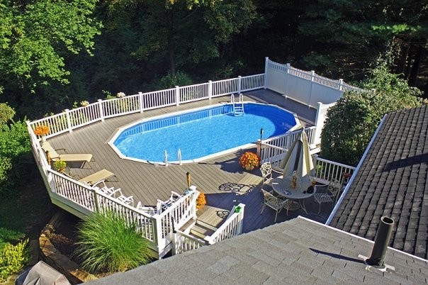Modelo de piscina de tamaño medio redondeada en patio trasero con entablado