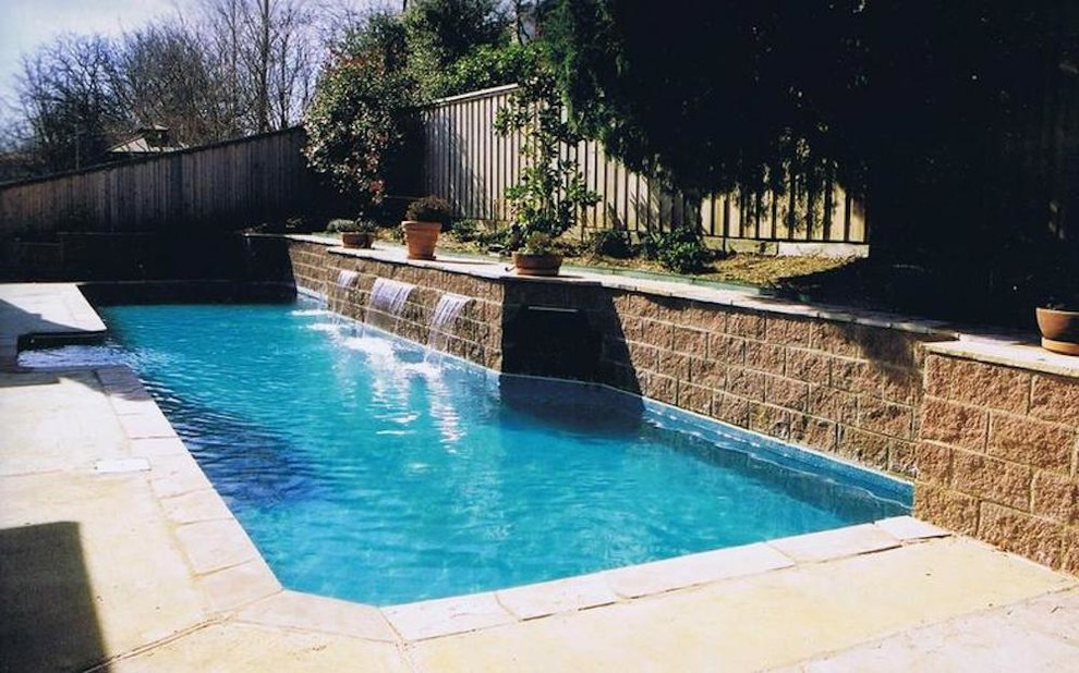 Modelo de piscina con fuente alargada contemporánea grande a medida en patio trasero con adoquines de hormigón