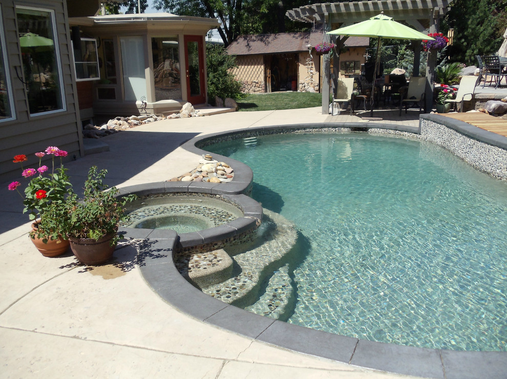 Photo of a large traditional back custom shaped lengths hot tub in Salt Lake City with concrete slabs.