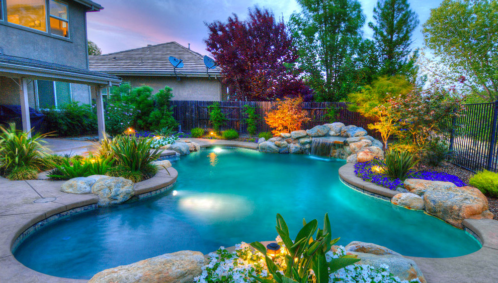 Large island style backyard concrete and kidney-shaped natural pool fountain photo in San Diego