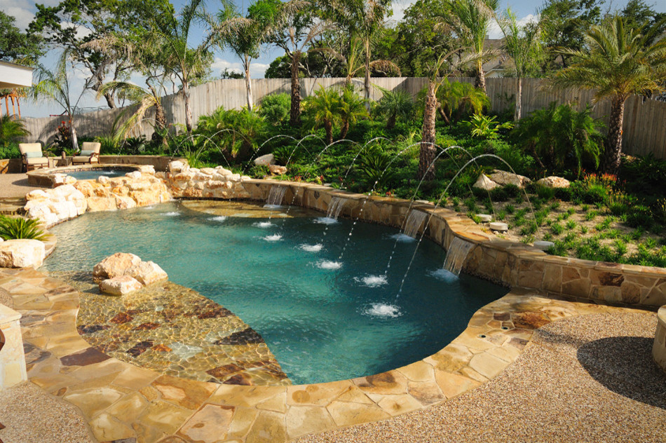 Cette photo montre une grande piscine naturelle et arrière sud-ouest américain sur mesure avec un point d'eau et des pavés en pierre naturelle.