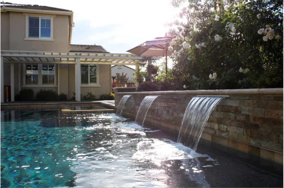 Photo of a mediterranean back rectangular lengths swimming pool in San Francisco with natural stone paving and a water feature.