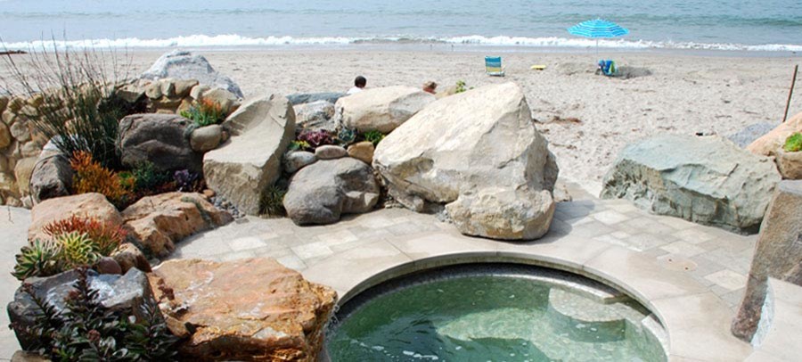 На фото: естественный бассейн произвольной формы на заднем дворе в морском стиле с джакузи и покрытием из каменной брусчатки с