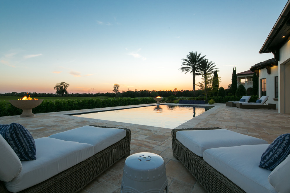 Großer Mediterraner Pool hinter dem Haus in rechteckiger Form mit Natursteinplatten in Miami