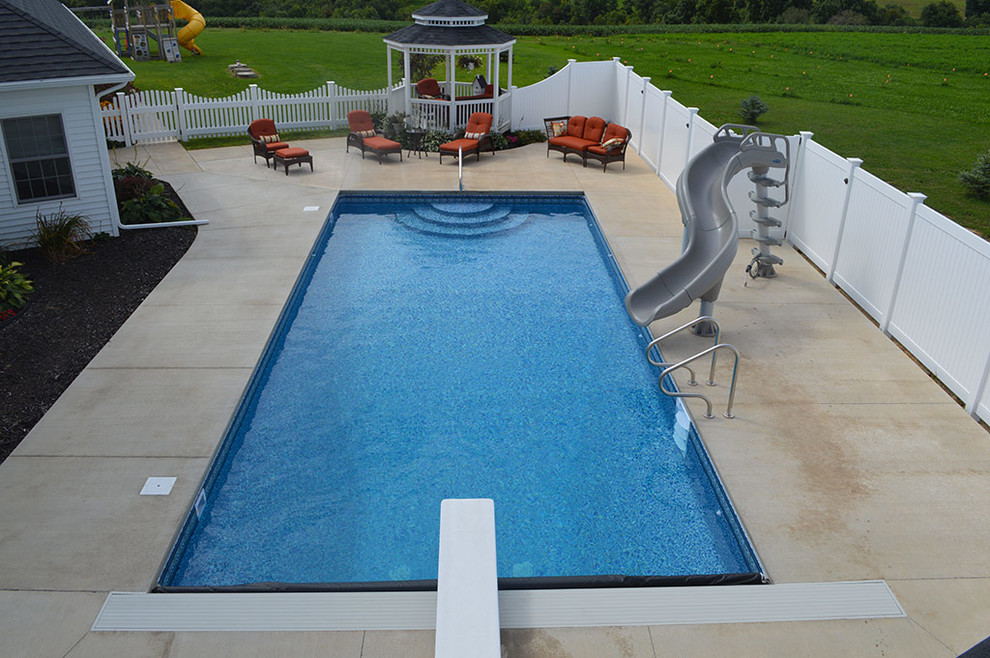 Foto di una piscina naturale moderna rettangolare di medie dimensioni e dietro casa con un acquascivolo e pavimentazioni in cemento