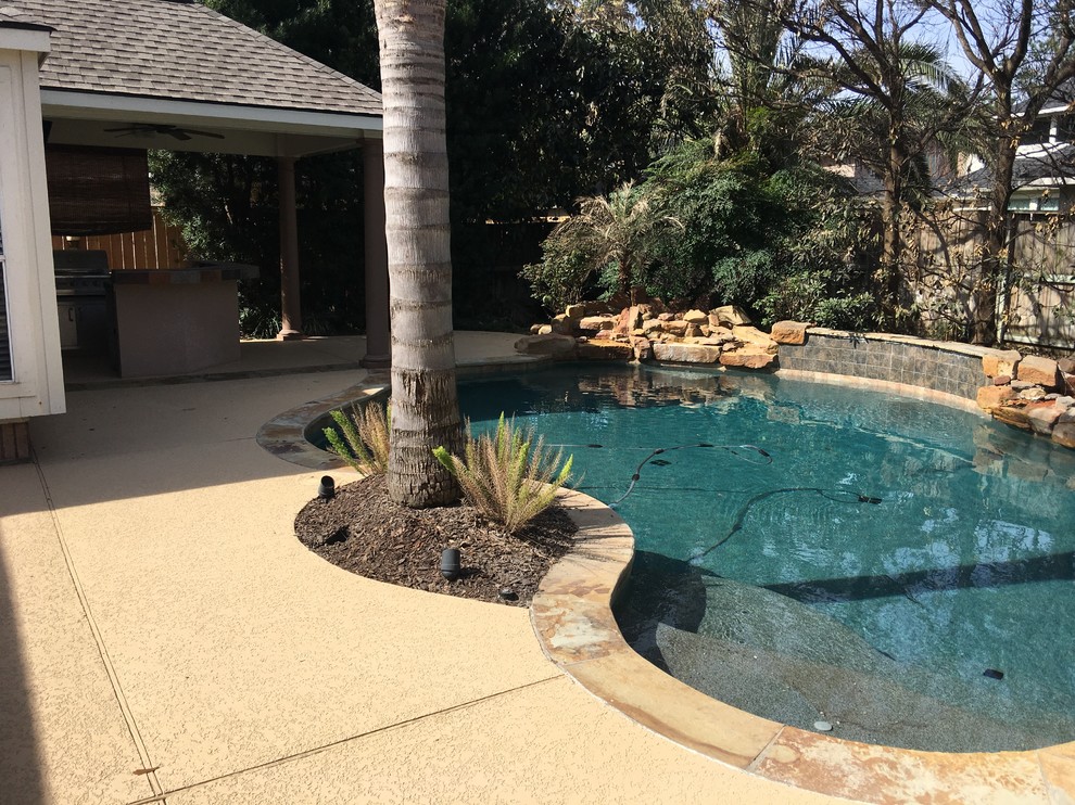 Esempio di una piscina chic a "C" di medie dimensioni e dietro casa con lastre di cemento