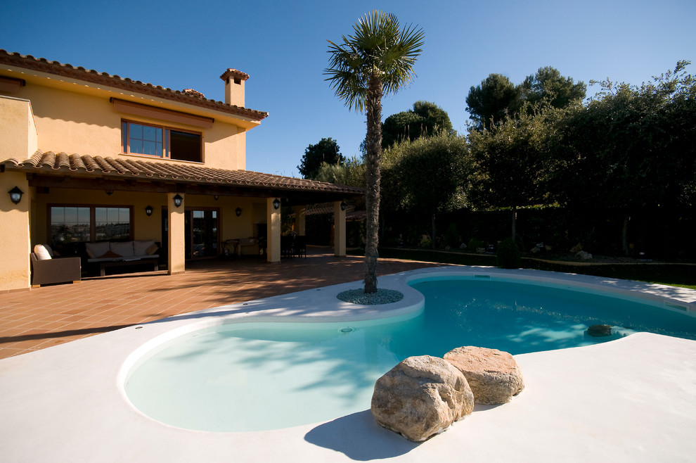 Esempio di una piscina a sfioro infinito mediterranea a "C" di medie dimensioni e dietro casa con lastre di cemento