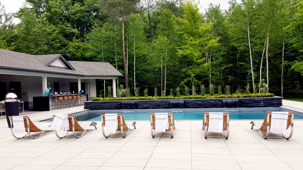 Imagen de piscina con fuente actual grande rectangular en patio trasero con losas de hormigón